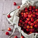 Freshly picked cherries on a ceramic plate, partially covered with a cloth — symbolizing growth, care, and the rewarding results of a well-cultivated streaming platform.